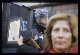 Fotografía de una mujer con un cuadro con la imagen de un detenido desaparecido